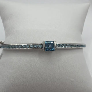 Sterling silver blue topaz bangle with square center stone and channel-set side stones