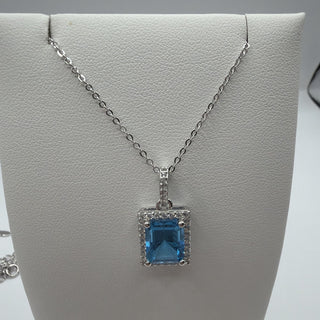 Sterling silver emerald-cut blue topaz halo necklace with white topaz