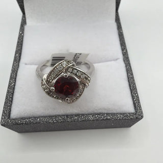 Sterling silver round garnet ring in a swirl of white topaz