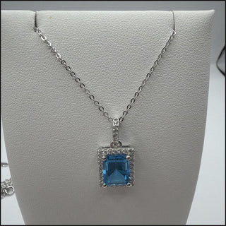 Sterling silver emerald-cut blue topaz halo necklace with white topaz